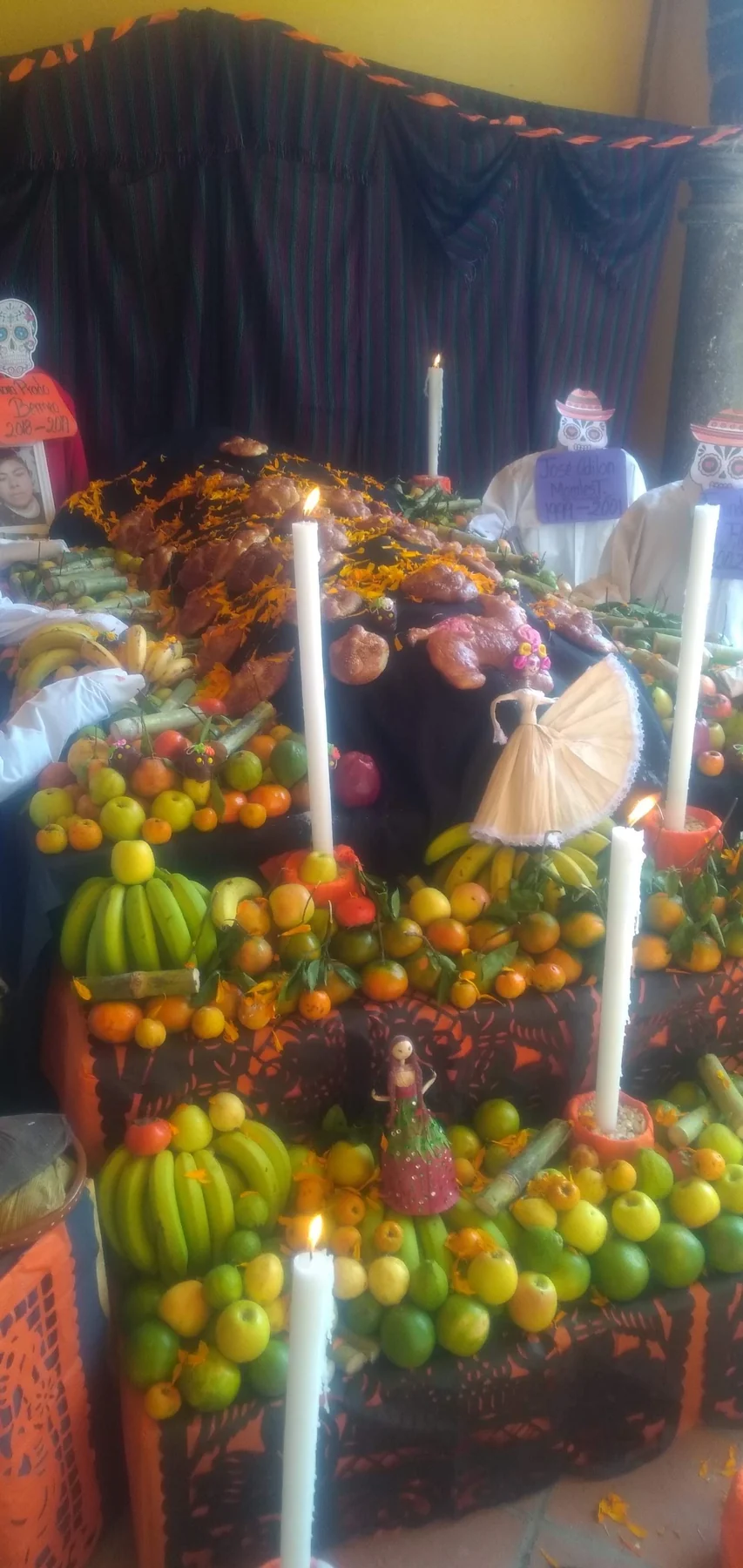 Ofrenda de Día de Muertos con panes, frutas, flores y veladoras